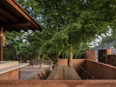 A wooden dining table with a bench and chairs in a cozy patio area, perfect for gatherings and social events