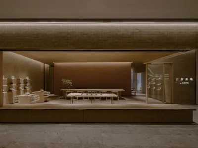 An empty retail space with a large window display, chairs, and potted plants, giving a clean and organized atmosphere