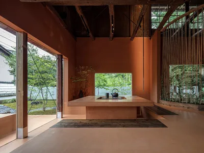 木質地板餐廳，配有大型餐桌與兩盆盆栽，透過窗戶自然光線照亮