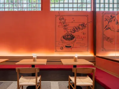 Warm and inviting Asian restaurant interior with wooden tables and chairs, a bowl on one table, and a cozy atmosphere
