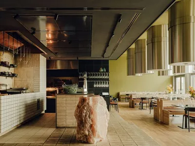 Modern kitchen with a large rock centerpiece, black countertops, and wine glasses, featuring a contemporary design and inviting atmosphere