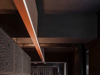 A modern kitchen with a wooden countertop, metal accents, and a dining table with chairs, set in a dimly lit space