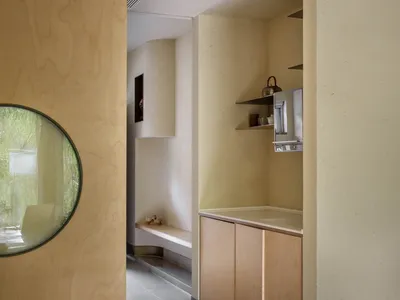Warm and cozy kitchen space with wooden floors and walls, featuring two sinks, a potted plant, a vase, and a chair, with various items scattered throughout
