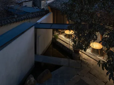 Modern Asian restaurant with glass walls, stone, and wood elements, featuring dining tables and chairs in a cozy atmosphere