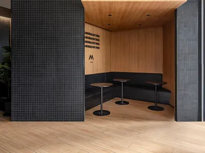 Modern restaurant dining area with black tile walls, multiple tables, and chairs, creating a sophisticated and inviting atmosphere