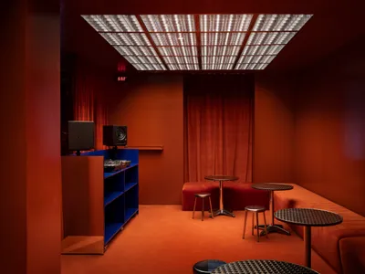 Warm and inviting orange room with a red curtain, two tables, chairs, and a couch, with a cozy seating area
