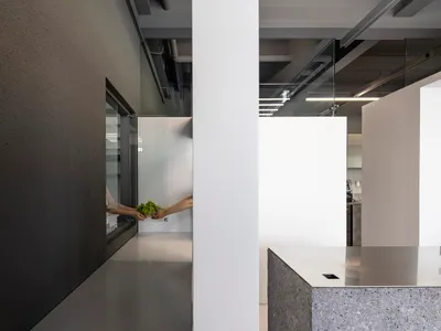 兩人在廚房中站立，配有水槽、工作檯面與休閒氛圍，周圍充滿自然光線