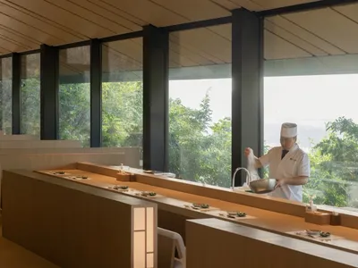 熱鬧的餐廳廚房，配有大窗戶、水槽、餐桌、椅子，以及準備食物的人員