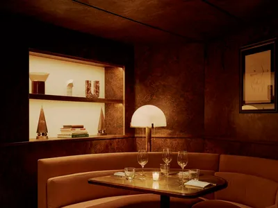 Dimly lit living space with two couches, a dining table, and wine glasses, adorned with books on the walls