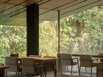 Modern restaurant interior with large windows, dining tables, and comfortable seating for guests