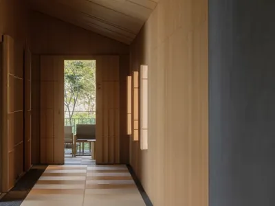 溫暖舒適的餐廳內部，木質牆面、餐桌、椅子，以及多扇窗戶灑入的自然光線