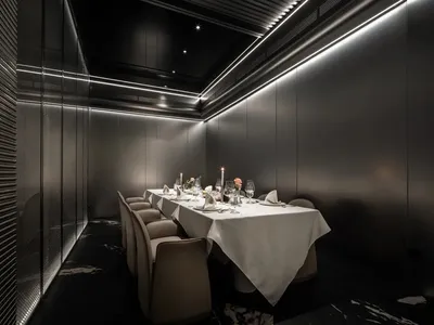 優雅的餐廳區域，配有長形木桌、多把椅子、酒杯、花瓶與盆栽植物，非常適合特殊活動或親密聚會