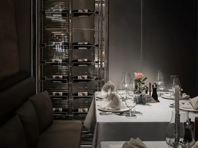 Dining area with a table set for dinner, featuring fine china, crystalware, wine glasses, and bottles, in a sophisticated and inviting atmosphere