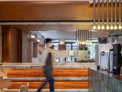 A modern restaurant interior with a counter featuring wood elements, marble, and various items, set in a comfortable and inviting atmosphere