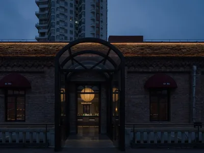 磚造建築物配大型拱門與玻璃門，懸掛吊燈並營造溫馨氛圍