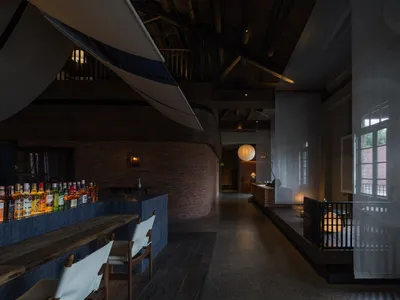 Cozy restaurant interior with wooden floors, brick walls, chairs, a dining table, and a potted plant