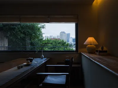 Cozy living space with a dining table near a window, allowing natural light and a view of the city outside