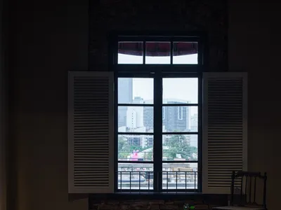 Cozy living space with natural light, a chair, two couches, and a dining table, overlooking a city street