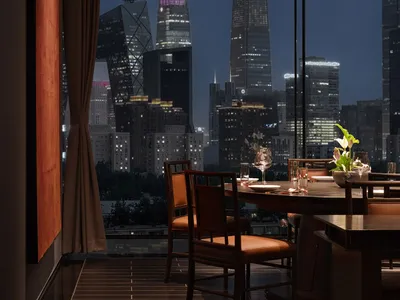 A dining area in a restaurant with a large table, wooden chairs, and wine glasses, creating a sophisticated and inviting atmosphere