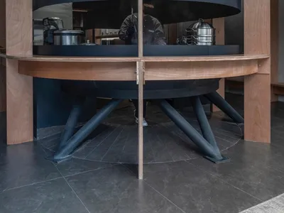 A modern Asian restaurant with a large black oven, wooden tables, and chairs, creating a warm and inviting atmosphere