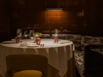 餐廳餐區內的白色餐桌，搭配酒杯、水杯與花瓶，周圍環繞舒適的客人座椅