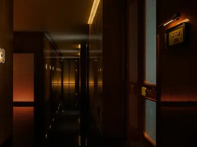 A dimly lit hotel hallway with a wooden floor, two doors on either side, and a minimalist design