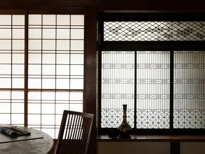 Dining area with a wooden table and modern chairs, surrounded by Asian-style decorations and a cozy atmosphere created by a fireplace
