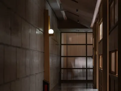 Empty hotel hallway with a concrete floor, glass doors, and two chairs for seating