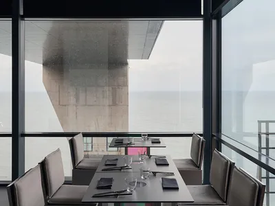 Elegant dining space with a large table, wine glasses, and ocean view
