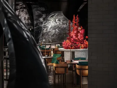 A modern restaurant dining area with multiple chairs and tables, featuring a metallic finish on the walls and a stylish atmosphere with black and red elements