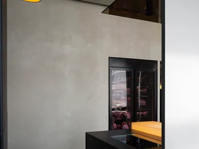 A modern dining area with a table and chairs, part of a larger space with a kitchen and refrigerator in the background