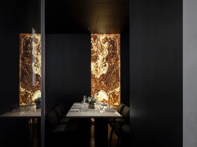 Elegant dining space with a black and white theme, featuring a large dining table, chairs, wine glasses, and vases, set in a high-end restaurant