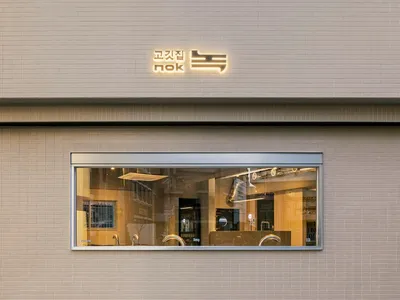 A modern Asian restaurant with a brick exterior, large windows, and comfortable seating areas