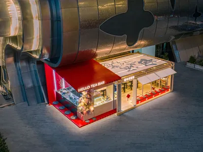 Cozy Asian restaurant with red roof, silver structure, dining tables, chairs, and potted plants, creating a modern and inviting atmosphere