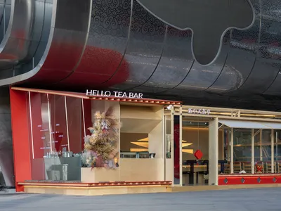 A restaurant with a red building, silver roof, and inviting atmosphere, featuring tables, chairs, and a counter