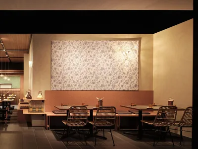 Empty restaurant with wooden floors and tables, featuring chairs placed around the dining area in a calm and inviting atmosphere