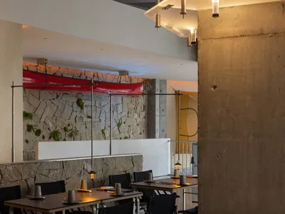 A modern restaurant interior with tables and chairs, cups on some tables, and a welcoming atmosphere