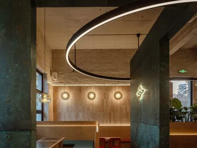 Dining area with chairs and tables, potted plants, metallic walls, and overhead lighting