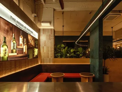 Modern restaurant interior with red benches, potted plants, and a welcoming atmosphere