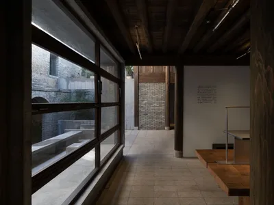 Modern restaurant interior with wooden floors and walls, large windows, and natural light