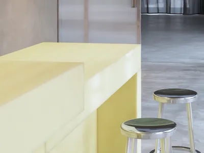 Modern kitchen with a yellow wood countertop and a black metal stool, creating a warm and inviting atmosphere