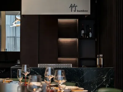 Elegant dining space with tables, chairs, wine glasses, and bottles, set in a sophisticated atmosphere