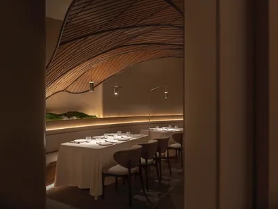 精緻餐廳內部，設有長形餐桌、白色桌巾與酒杯，周圍環繞舒適座椅