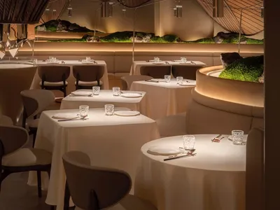 寬敞的餐廳餐區設有多張桌椅、白色桌布、酒杯與杯子，營造出精緻而溫馨的氛圍