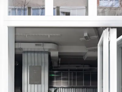 休閒餐廳內部，一隻狗狗置身中央，周圍環繞著椅子與桌椅，左側擺放盆栽，營造輕鬆氛圍