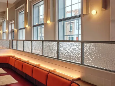 rows of wooden benches and dining tables in a restaurant or cafeteria with natural light from windows