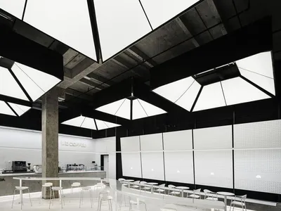 Spacious modern restaurant interior with multiple dining tables, chairs, and high ceilings