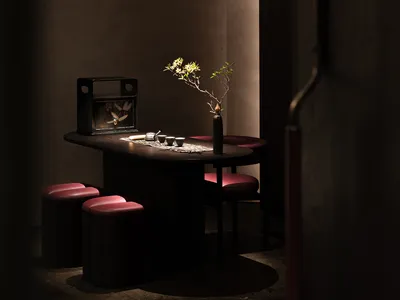 A small kitchen area with a dining table surrounded by chairs, featuring a vase and two cups, creating a cozy and inviting atmosphere