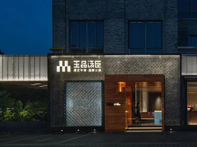 夜晚飯店入口，大型建築以磚牆立面為特色，搭配盆栽與牆上時鐘，展現優雅與精緻風範