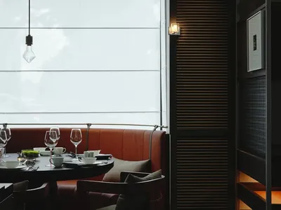 Sophisticated dining area with a large window, multiple chairs, and wine glasses on a dining table